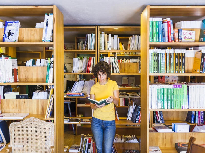 reader standing between shelves inside a goodwill bookstore in Sarasota exploring affordable used books