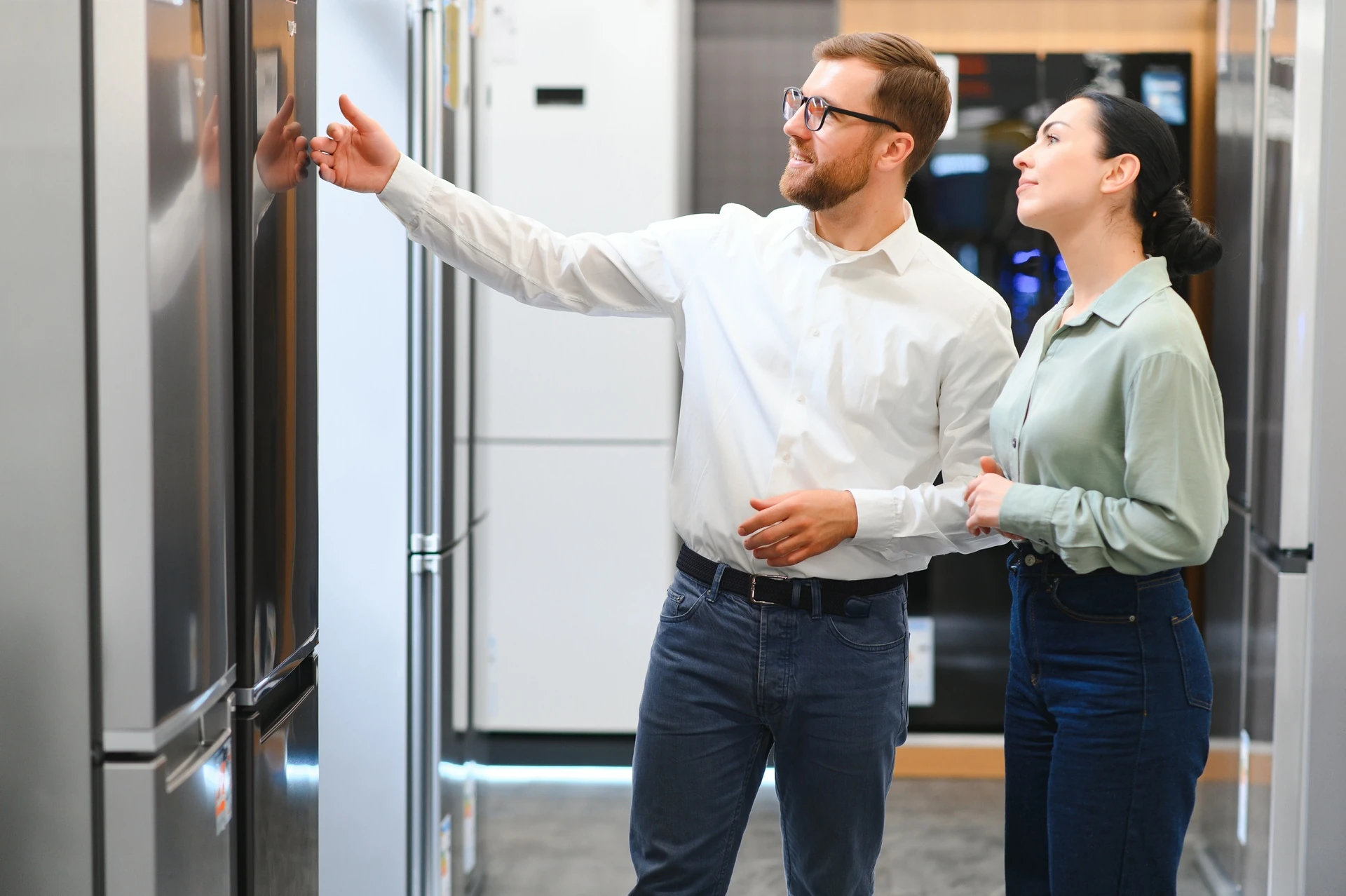 shop assistant demonstrates appliances feature to young woman