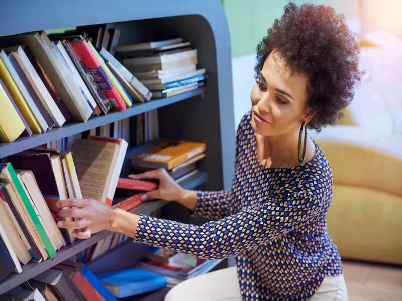 woman selecting used books from a shelf in a well organized goodwill bookstore in Sarasota