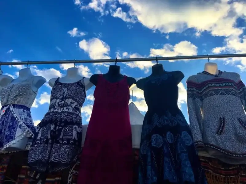 close view of mixed clothing styles including jackets, tops and dresses in a used clothing store
