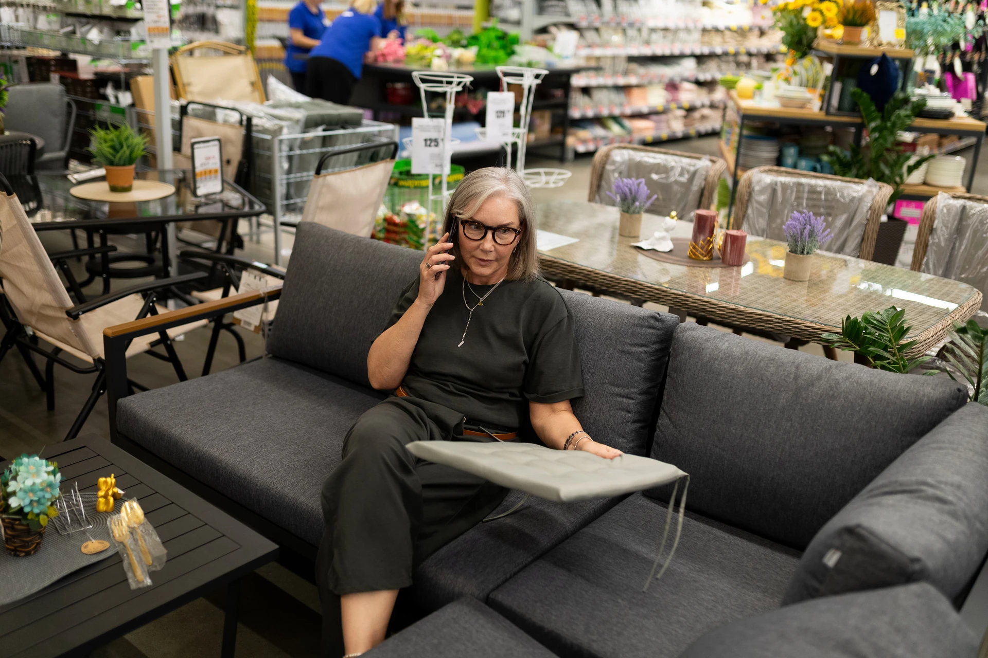 old lady discussing over phone sofa and table options at a goodwill furniture store