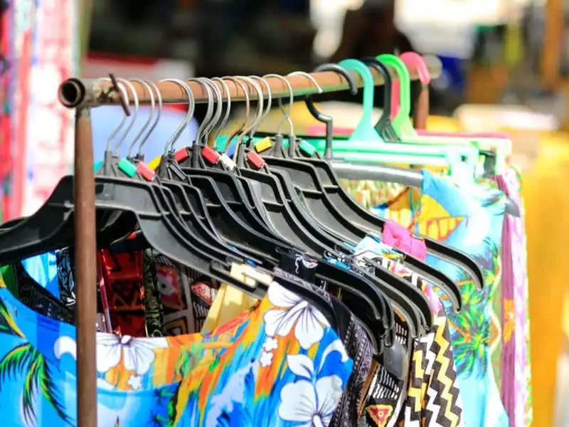 rows of asorted second hand clothing store items on hangers