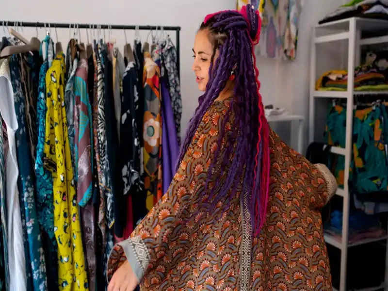 shopper examining clothing while standing between full racks of apparel at a bright thrift store clothing